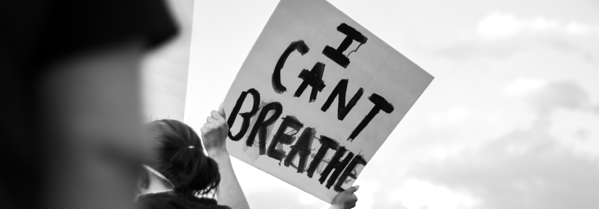 Female protester holding up a sign that says "I CAN'T BREATHE"