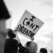 Female protester holding up a sign that says "I CAN'T BREATHE"