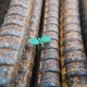 Tiny bud of a green plant, growing in the cracks between old metal pipes